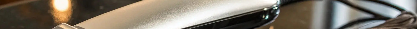 Andis T-Outliner trimmer with its carbon-steel T-blade on a barber station.