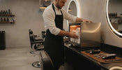 Barber loading clean towels into a countertop towel warming cabinet