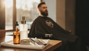 Beard products arranged on a professional barber workstation beside a client