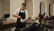 Barber preparing warm shaving lather at a professional barbershop station