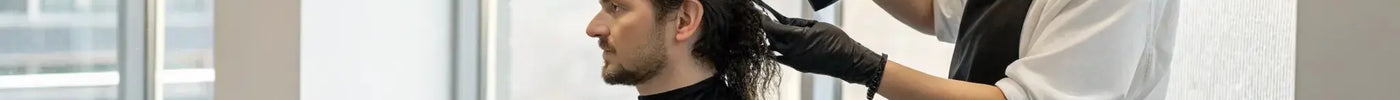 A professional applying hair fibers to a client's thinning hairline.