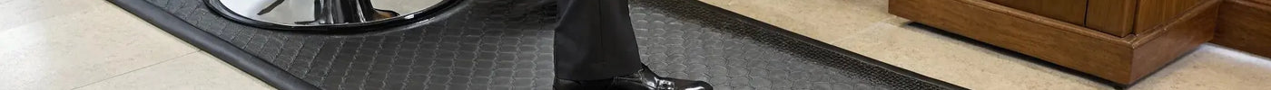 Thick anti-fatigue barber mat at a salon station for all-day comfort and posture support.