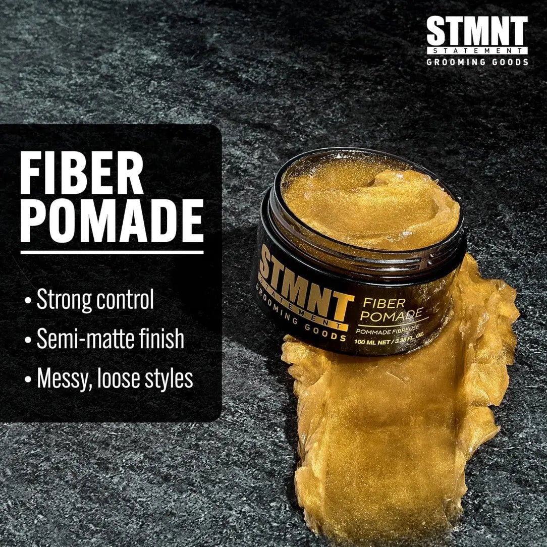 STMNT Fiber Pomade jar with pomade on a black background