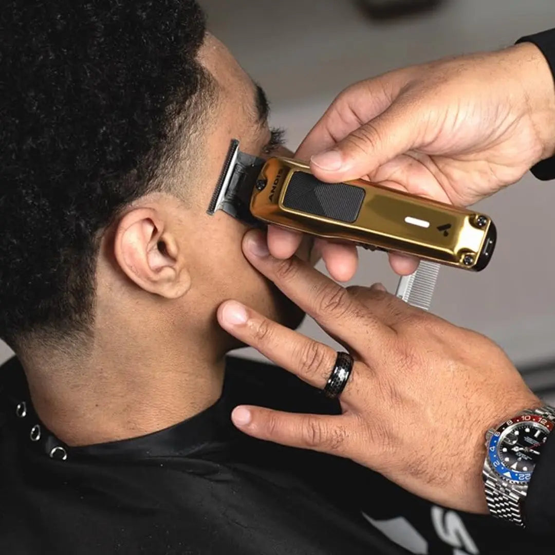 “Andis Phenom Cord/Cordless Trimmer in Gold on its charging stand”