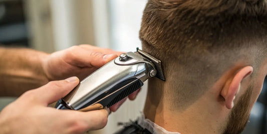 A professional barber uses small hair clippers for a precise neckline trim.