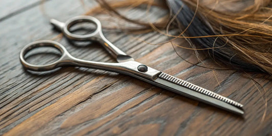 A pair of professional hair shears for stylists, resting next to a lock of cut hair.
