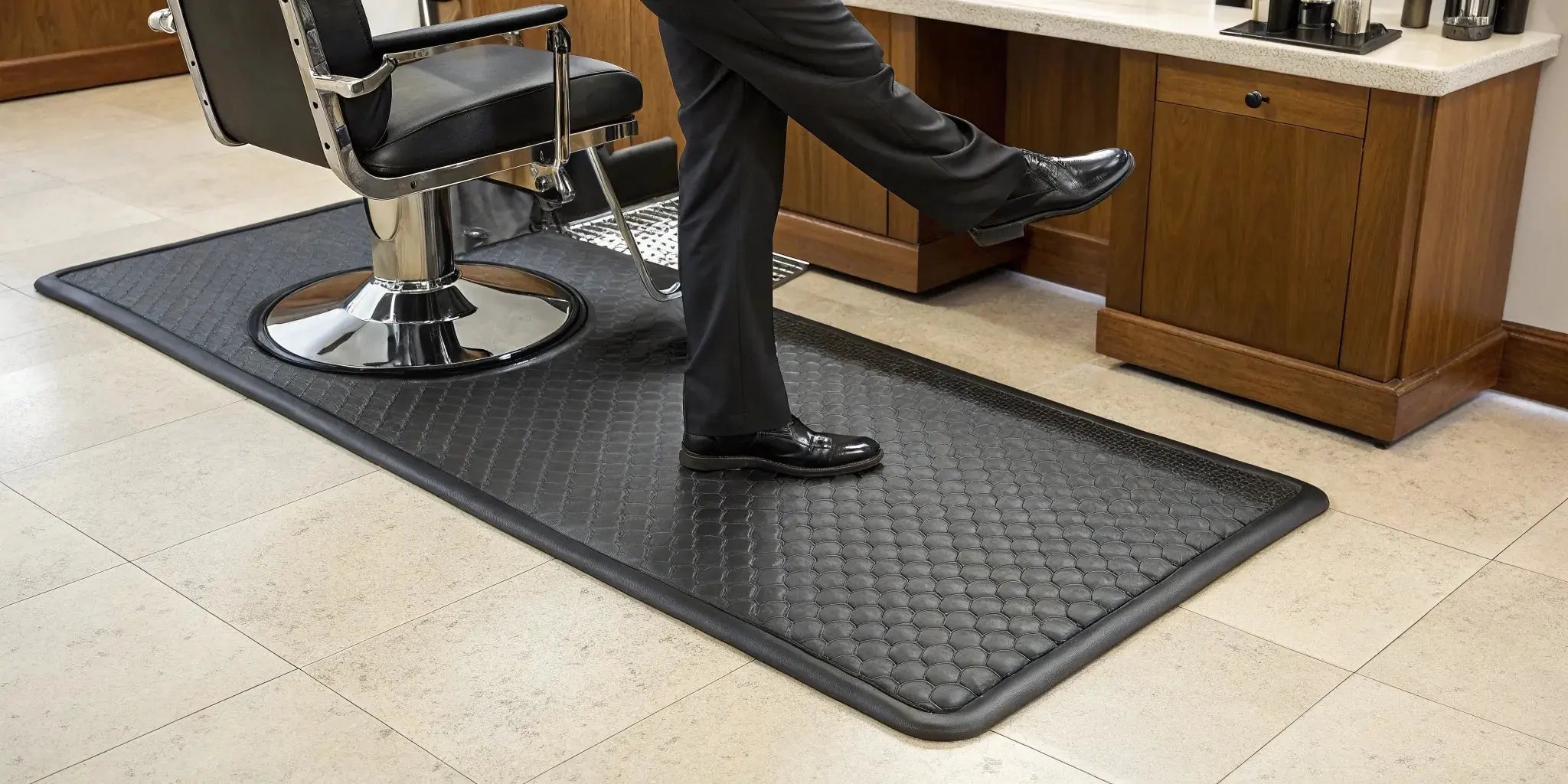 Thick anti-fatigue barber mat at a salon station for all-day comfort and posture support.
