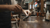 Professional barber adjusting clipper blade screws on a workbench for zero gapping