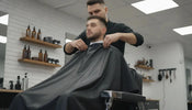 Professional barber adjusting a cutting cape over a client in a modern barbershop