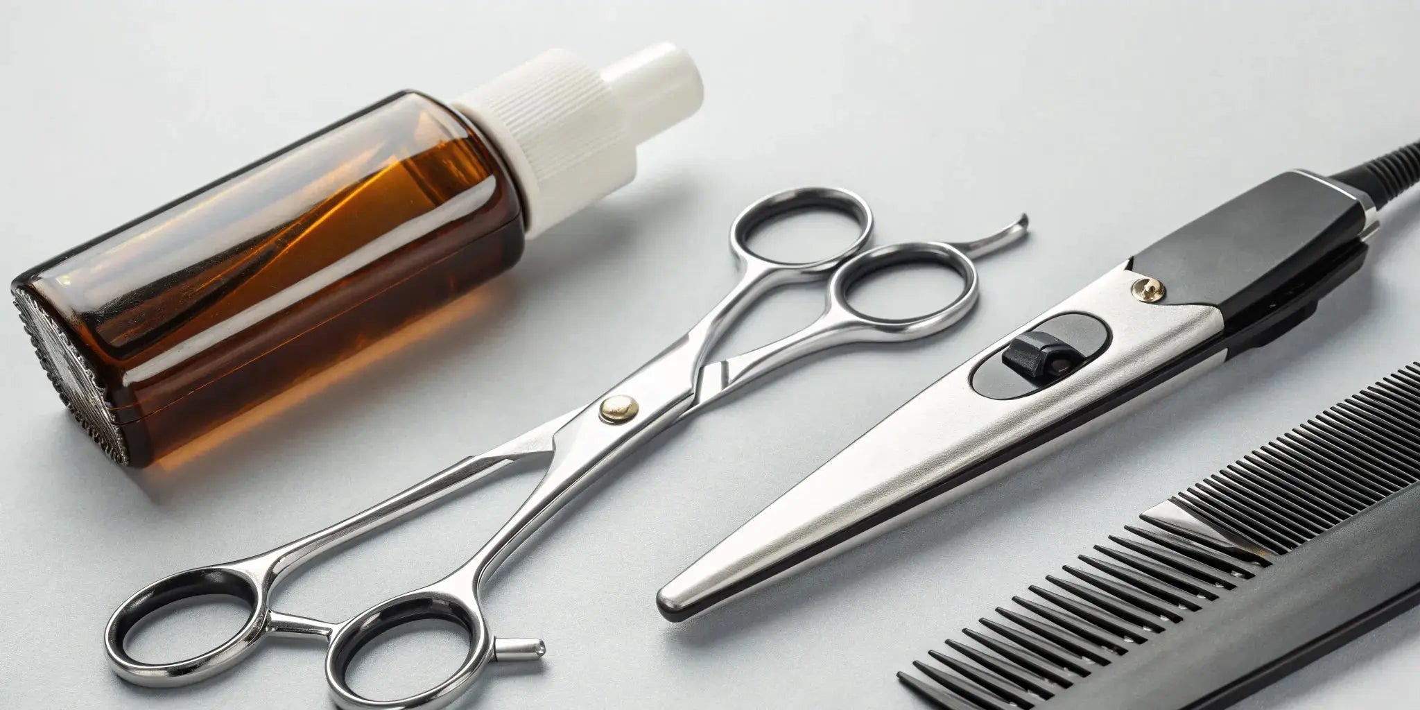A bottle of clipper oil with an electric clipper and comb, ready for maintenance.