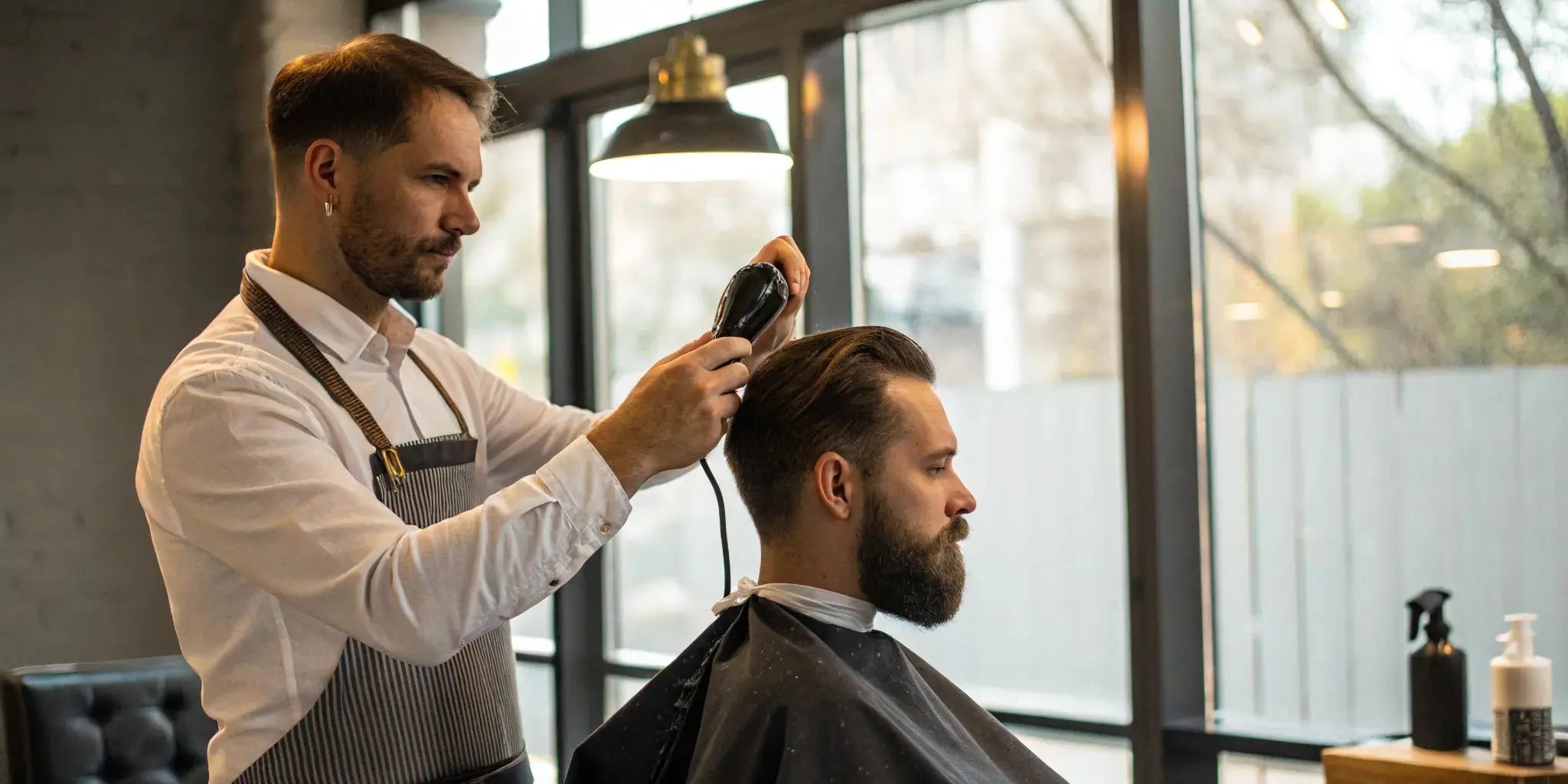 Barber styling a client's hair with clippers before applying hair fibers.