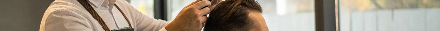 Barber styling a client's hair with clippers before applying hair fibers.