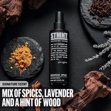 STMNT grooming spray bottle with spices, lavender, and wood on a dark surface