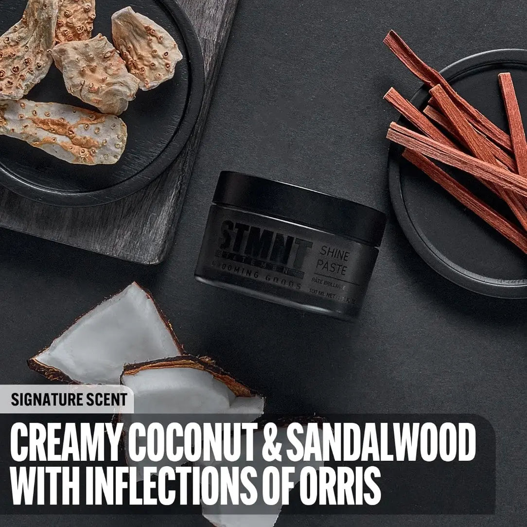 STMN Shine Paste jar with coconut pieces, sandalwood sticks, and text describing scent on a dark surface.