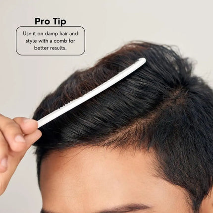 Person styling hair with a comb on a neutral background