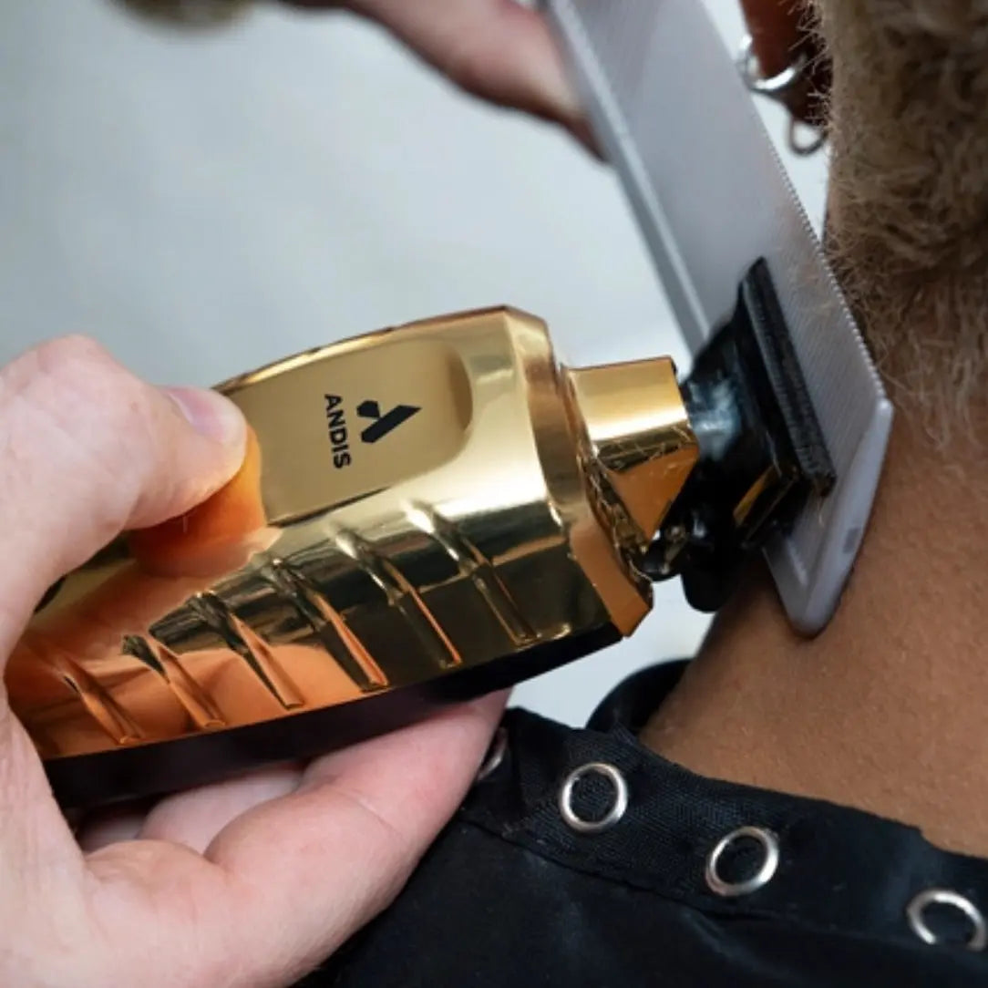 Gold Andis hair clipper being used on a person's head