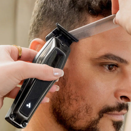 Person using a hair trimmer on their head with a neutral background andis Recon 