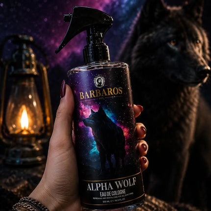 A hand holds a bottle of Barbaros Alpha Wolf Eau de Cologne, featuring a wolf graphic on a dark label, with a lit lantern on the left and a large wolf silhouette on the right against a starry night sky.