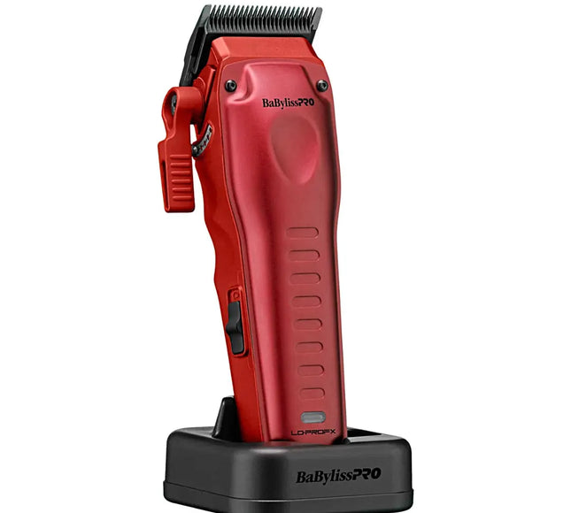 A red BaBylissPRO cordless hair clipper standing upright on a black charging dock against a plain white background.