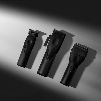 Three black cordless hair clippers with different cutting heads arranged diagonally on a dark gray gradient background.