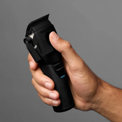 A hand holding a black Babylift Power7 cordless hair clipper against a solid gray background.