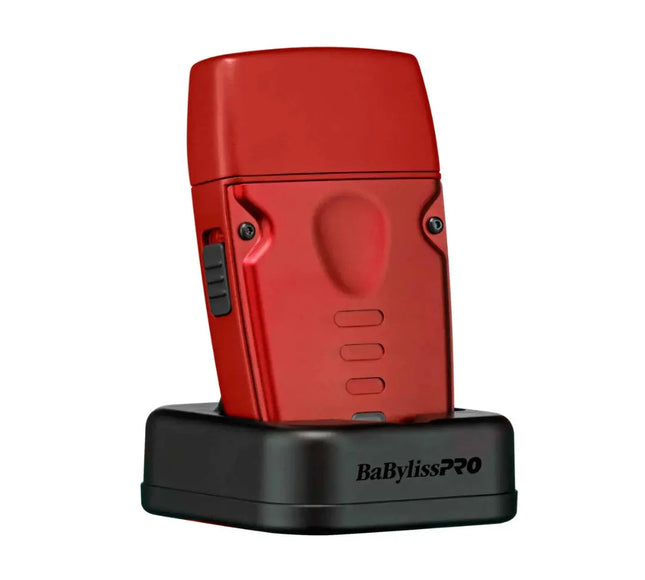 A red BaBylissPRO hair straightener standing upright on a black charging dock against a plain white background.