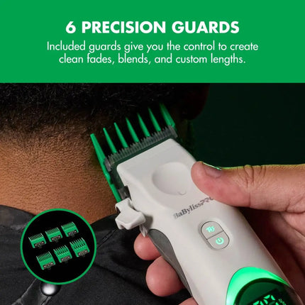 A close-up of a hand using a BaBylissPRO Tomb45 White Wireless with a green guide comb on a person's head, with text at the top reading '6 PRECISION GUARDS' and a small inset showing the included guard attachments.