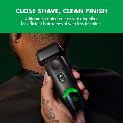 A close-up of a man's neck and hand holding a Babylisspro tomb45 Shaver electric shaver with a green illuminated display, set against a dark green background with a green banner at the top reading 'CLOSE SHAVE, CLEAN FINISH'.