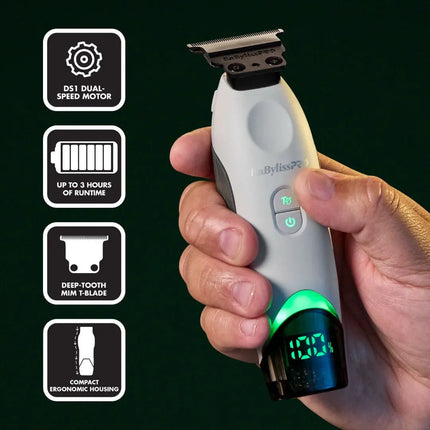 A hand holds a BaBylissPRO Tomb45 White Wireless-Charging Trimmer – FXT45TTWdual-speed electric hair trimmer against a dark green background, with four feature callout icons on the left highlighting the DS1 dual-speed motor, up to 3 hours of runtime, deep-tooth mini T-blade, and compact ergonomic housing.