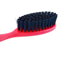 A close-up of a hairbrush showing a bright pink handle and black bristles on a plain white background.