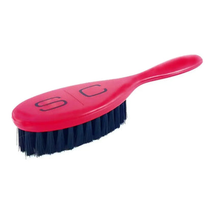 A pink hairbrush with dark blue bristles, featuring the stylized 'SC' logo on the handle, set against a plain white background.