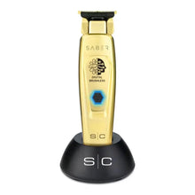 Saber Gold hair trimmer with black stand on a white background