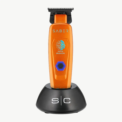 An orange SABER digital brushless electric trimmer standing upright on a black charging dock against a light gray background.
