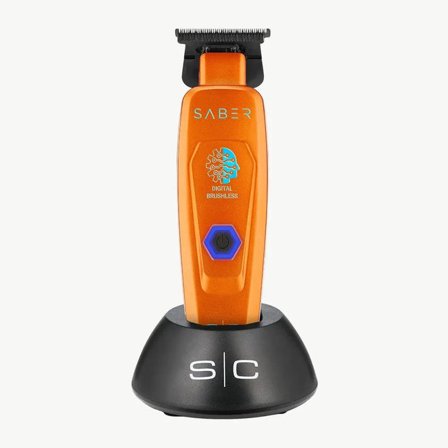 An orange SABER digital brushless electric trimmer standing upright on a black charging dock against a light gray background.