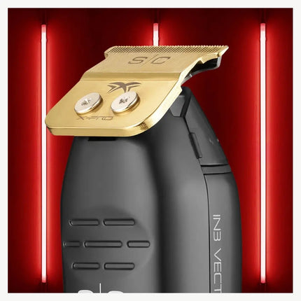 A close-up of a black electric hair clipper with a metallic gold guard blade, set against a red background with vertical light tubes.