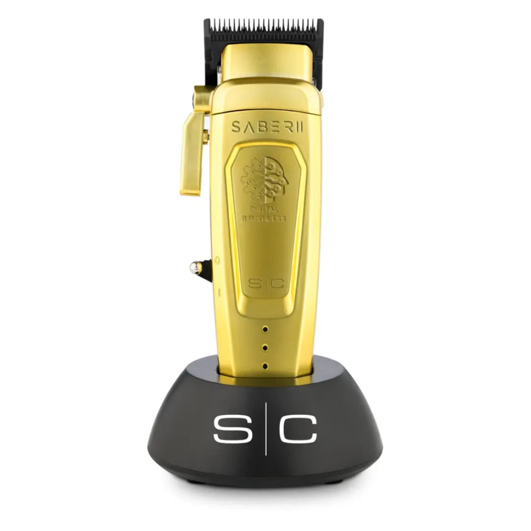 Saber II professional cordless hair clipper in gold color, with a black stand, displaying the Saber 2 brand name.