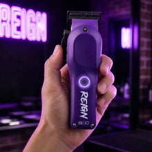 stylecraft  Purple hair trimmer with 'Reign' branding held in a hand against a dark background with neon lights.