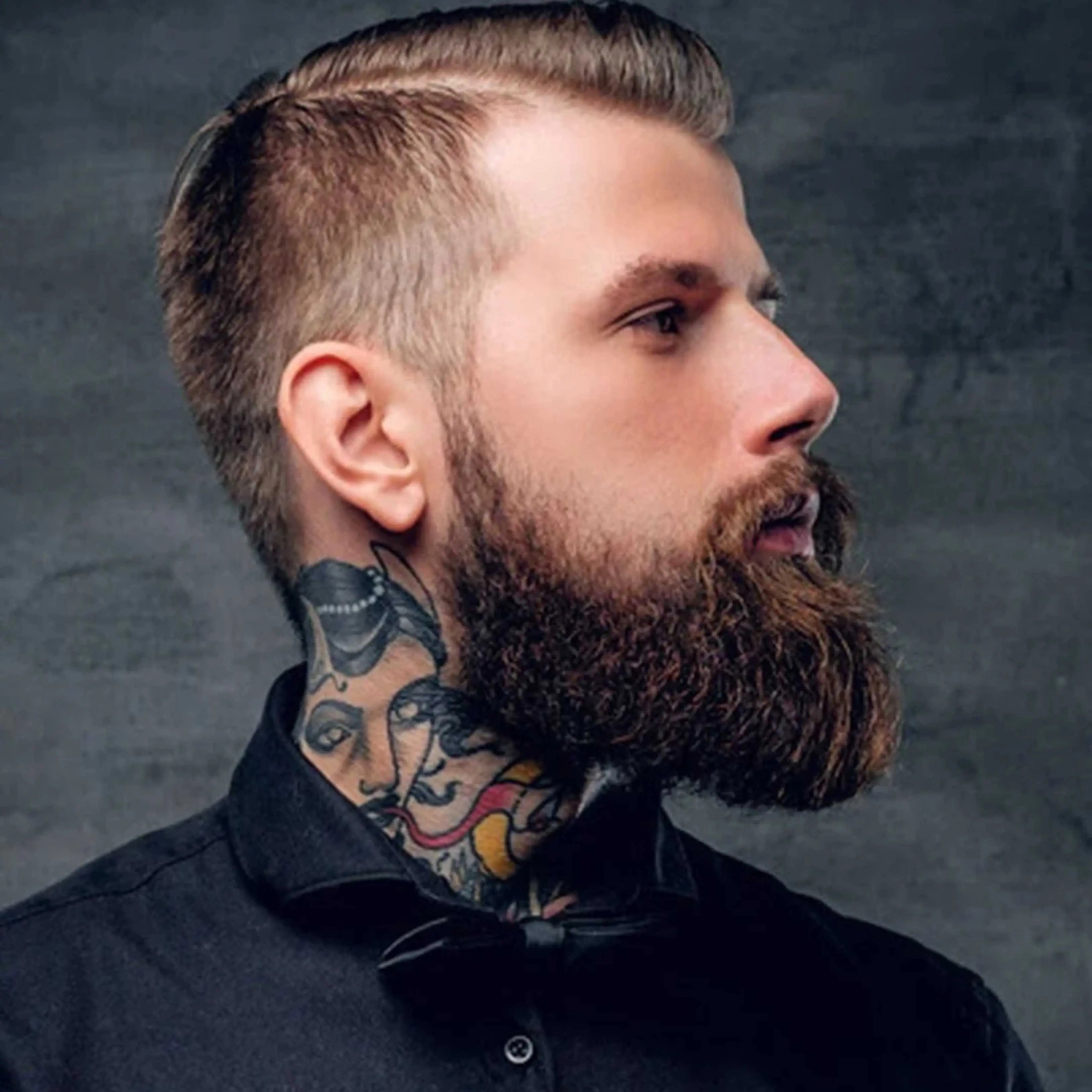 Man with a beard and tattoos on his neck against a dark background