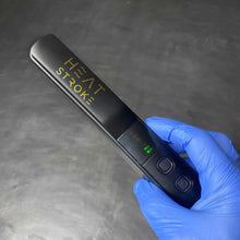 Hand holding a black device labeled 'Heat Stroke' with a digital display on a gray background.