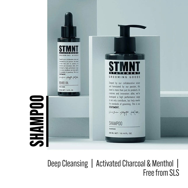 Two bottles of STMNT grooming products on a gray background